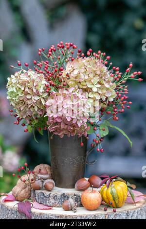 bouquet de fleurs d'hortensia et de hanches roses dans une coupe en cuivre vintage Banque D'Images