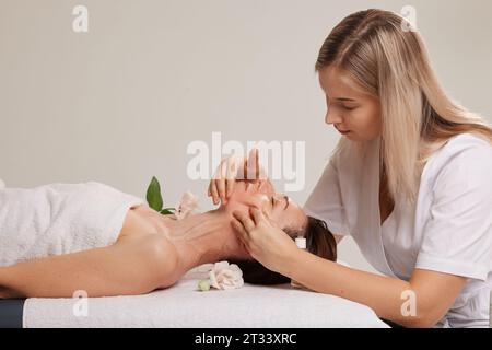 cosmétologue faisant un massage facial à une fille dans un salon de beauté, des procédures de beauté pour lisser la peau Banque D'Images