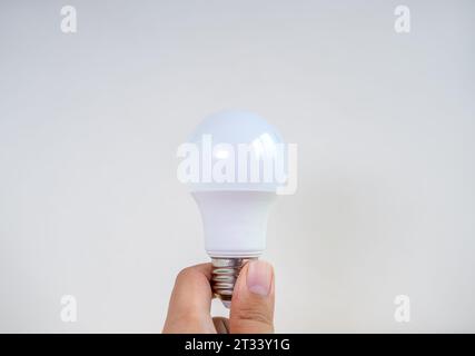 Ampoule LED blanche moderne ou ou lampe d'économie tenant à la main isolée sur fond blanc. Recycler l'énergie et la créativité des concepts de pensée d'idée Banque D'Images