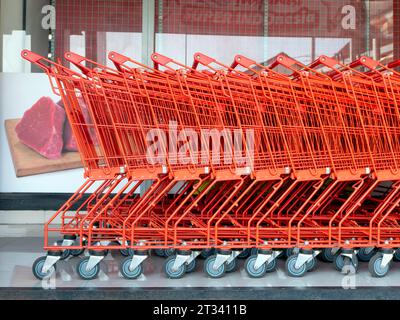 Une rangée de chariots rouges dans un supermarché moderne. Banque D'Images