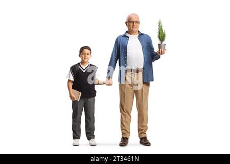 Portrait en longueur d'un homme avec un petit arbre dans un pot tenant un écolier par la main isolé sur fond blanc Banque D'Images