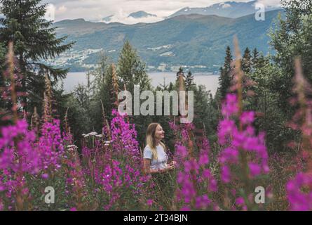 Femme dans les montagnes parmi les fleurs de l'herbe à feu en Norvège Banque D'Images