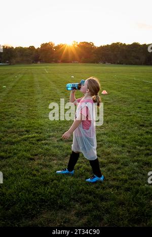 Jeune fille prenant une pause d'eau après la pratique de football Banque D'Images