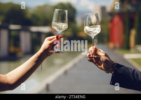 Gros plan de couple verres à vin blanc clinking sur fond de nature. Concept de fête de boissons amusantes. Banque D'Images