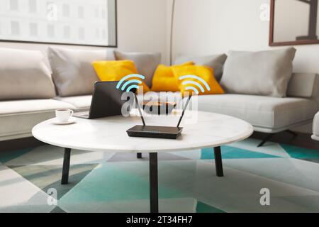 Routeur brillant et noir debout sur la table dans l'appartement. Un dispositif électronique fonctionne, transmettant un signal à partir de ses antennes. Connexion Internet Banque D'Images