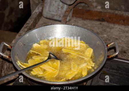 Le processus de friture des chips de banane avec de l'huile chaude, sur une grande poêle. Banque D'Images