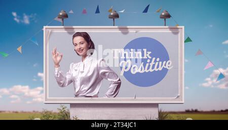 Femme heureuse avec humeur positive sur la publicité de panneau d'affichage et citation de motivation : penser positif Banque D'Images