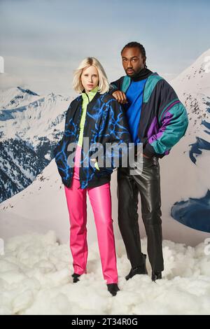 jeune couple élégant en tenue chaude posant main sur épaule avec toile de fond enneigée, concept d'hiver Banque D'Images