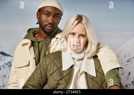 portrait d'un couple multiracial voguish dans une tenue chaleureuse et vibrante regardant la caméra, concept d'hiver Banque D'Images