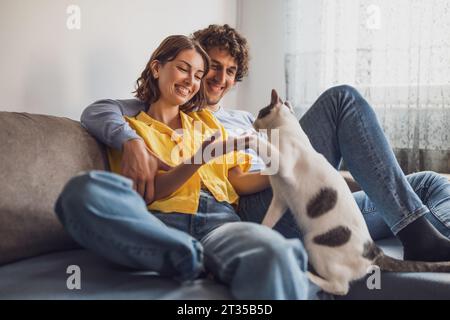 Portrait de jeune couple heureux et leur chat à la maison. Banque D'Images