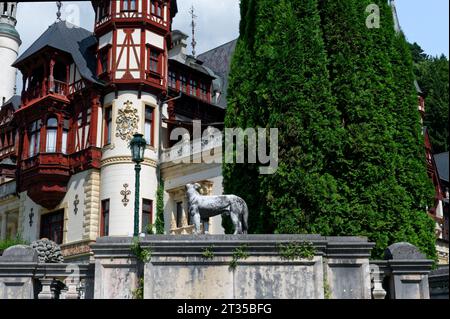 Beauté de l'extérieur du château de peles par une journée ensoleillée, statue de chien baignée dans la lueur chaude de la lumière du soleil. Banque D'Images