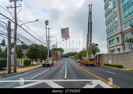 Drapeau américain suspendu à un camion de pompiers au-dessus d'une rue fermée en préparation pour la course de 5K, Conshohocken, PA États-Unis Banque D'Images