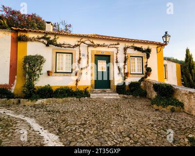 Une scène idyllique avec une maison traditionnelle de deux étages située au sommet d'une route pavée pittoresque Banque D'Images