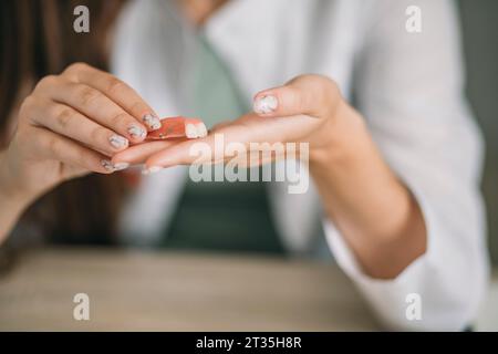 Prothèse dentaire d'enfant dans les mains du médecin gros plan. Photo conceptuelle dentaire. Dentisterie prothétique. Fausses dents Banque D'Images