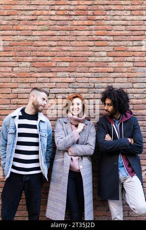 Portrait de trois amis debout à un mur de briques Banque D'Images