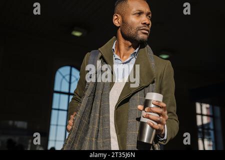 L'homme élégant avec tasse réutilisable en sortant de la gare Banque D'Images