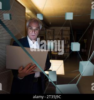 Image composite numérique de l'homme d'affaires utilisant un ordinateur portable dans le bureau Banque D'Images
