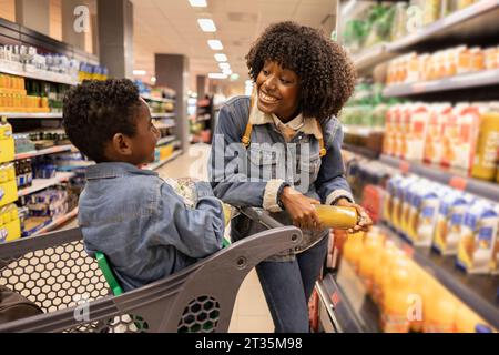 Heureuse jeune femme shopping dans le supermarché avec fils Banque D'Images