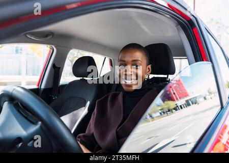 Bonne jeune femme assise en voiture Banque D'Images