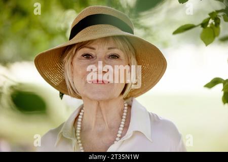 Femme âgée portant un chapeau dans le parc Banque D'Images