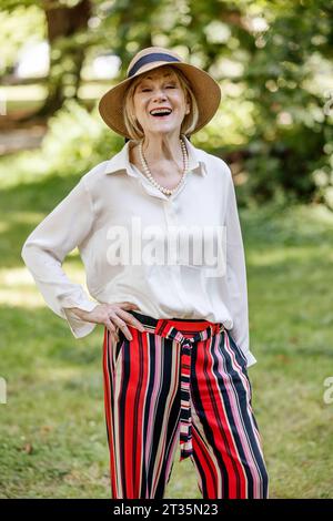 Femme âgée avec la main sur la hanche riant au parc Banque D'Images