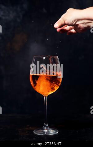 Main de femme ajoutant des glaçons au verre d'Aperol spritz Banque D'Images