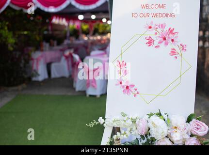 Tableau blanc de maquette de chevalet avec modèle de carte de voeux de signe de bienvenue floral extérieur Banque D'Images