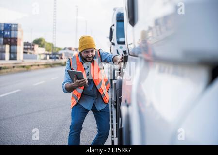 Chauffeur de camion souriant examinant camion avec tablette PC Banque D'Images