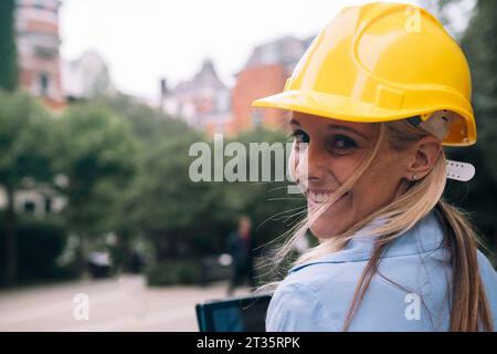 Heureux ingénieur regardant par-dessus l'épaule portant le casque jaune Banque D'Images