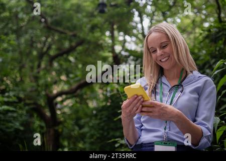 Médecin souriant à l'aide d'un téléphone intelligent Banque D'Images