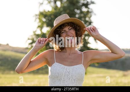 Femme portant un chapeau sortant de la langue au beau jour Banque D'Images