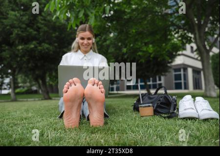 Heureuse femme d'affaires travaillant sur ordinateur portable dans le parc de bureaux Banque D'Images