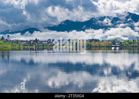 Allemagne, Bavière, Hopfen am See, lac Hopfensee avec village et nuages bas en arrière-plan Banque D'Images