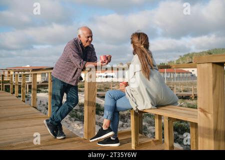 Heureux couple senior avec des tasses à café passant du temps ensemble sur la promenade Banque D'Images