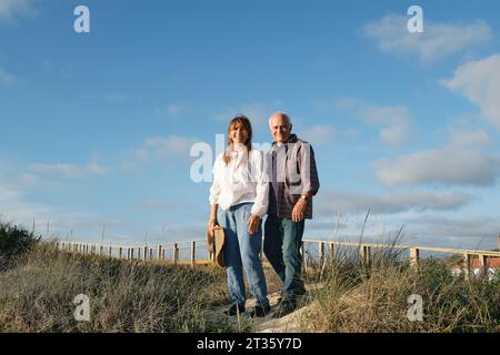 Heureuse femme senior debout avec l'homme sous le ciel nuageux Banque D'Images