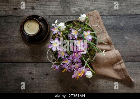 Tasse de café et fleurs printanières dans un seau en métal debout sur une table en bois Banque D'Images