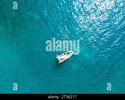 Vue drone d'un groupe de plongeurs nageant près d'un bateau à moteur flottant Banque D'Images