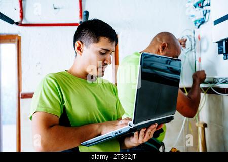 Ingénieur utilisant un ordinateur portable avec un collègue travaillant en arrière-plan Banque D'Images