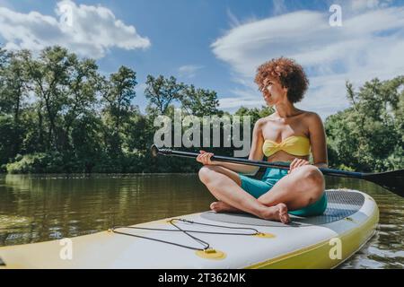 Jeune femme assise sur paddleboard dans le lac Banque D'Images