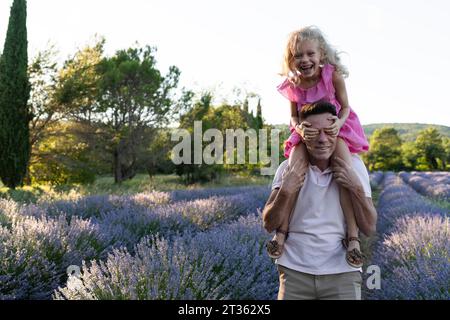 Fille heureuse couvrant les yeux et s'amusant avec le père dans le champ de lavande Banque D'Images