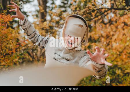Fille joyeuse portant costume de momie et faisant des gestes dans le jardin Banque D'Images