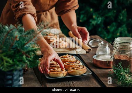 Femme arrangeant des petits pains à la cannelle sur le plateau à la maison Banque D'Images