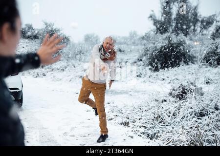 Homme senior lançant une boule de neige sur son fils Banque D'Images