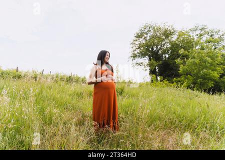 Femme enceinte debout au milieu de l'herbe Banque D'Images