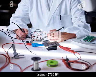 Mains de scientifique travaillant sur la carte de circuit imprimé avec des outils Banque D'Images
