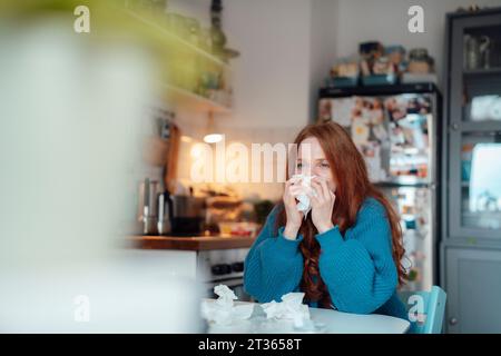 Femme malade soufflant le nez sur les tissus à la maison Banque D'Images