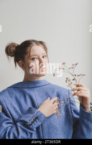 Adolescente portant un blazer bleu à l'envers avec des fleurs devant le mur Banque D'Images
