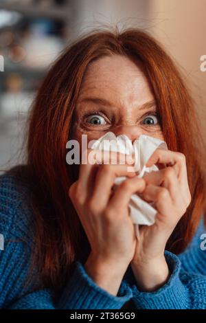 Redhead femme soufflant nez sur papier de soie à la maison Banque D'Images