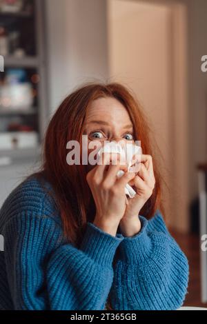 Redhead femme soufflant nez sur papier de soie Banque D'Images