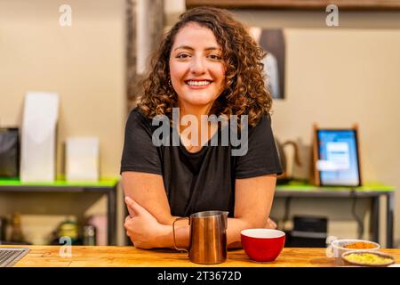 Femme souriante penchée à table dans le café Banque D'Images